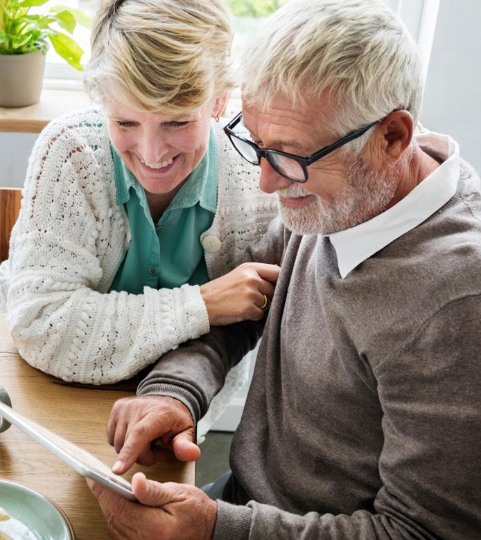 An elderly couple smiling at an ipad